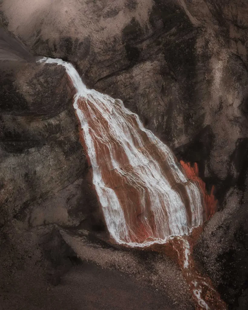 Bird view on the red Raudufossar waterfall in the moss-green landscape of the highlands of Iceland