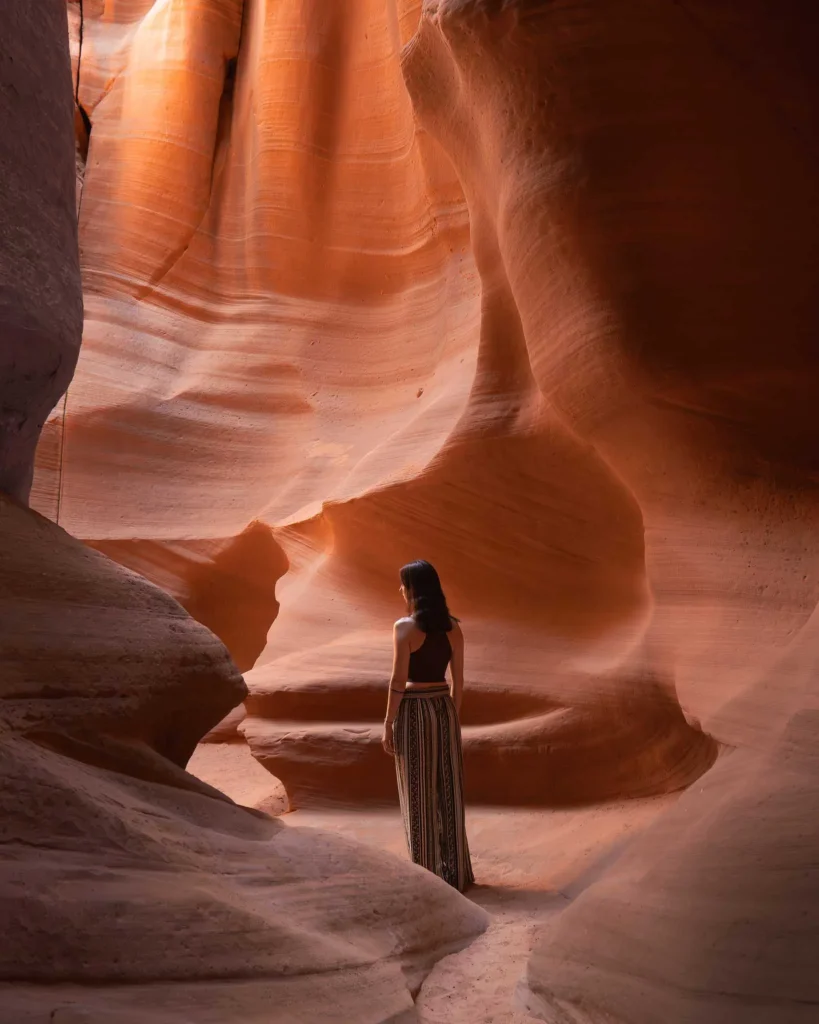 A woman stands in Antelope Canyon, which is mystical in the warm sunlight.